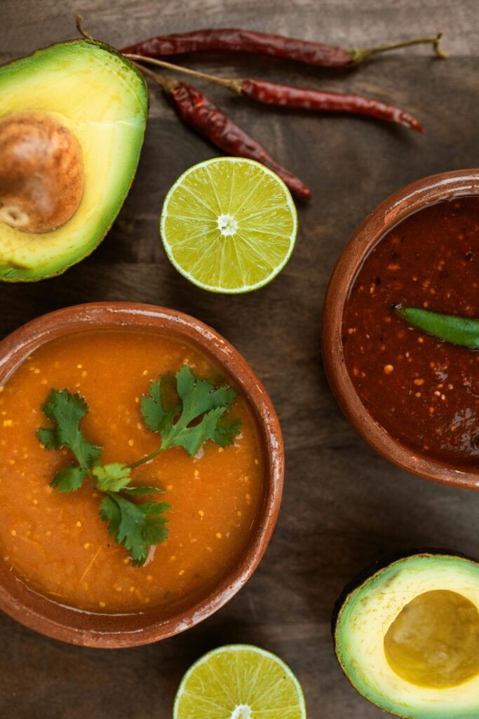 Top view of Mexican salsas with avocado and lime slices, vibrant and delicious.